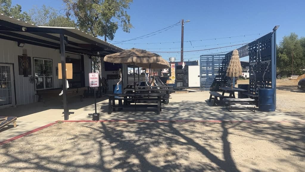 The patio in daylight with the trailer and tables